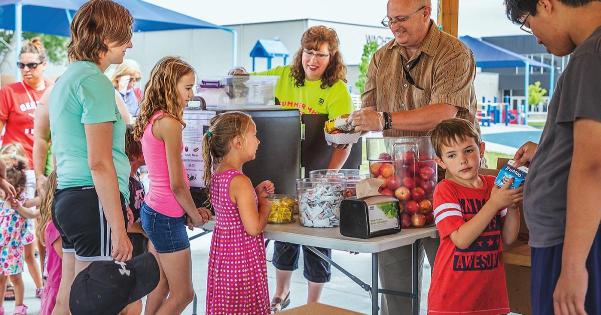 Families line up for a  free picnic lunch, courtesy of the Summer Feeding Program, at a Bismarck park.