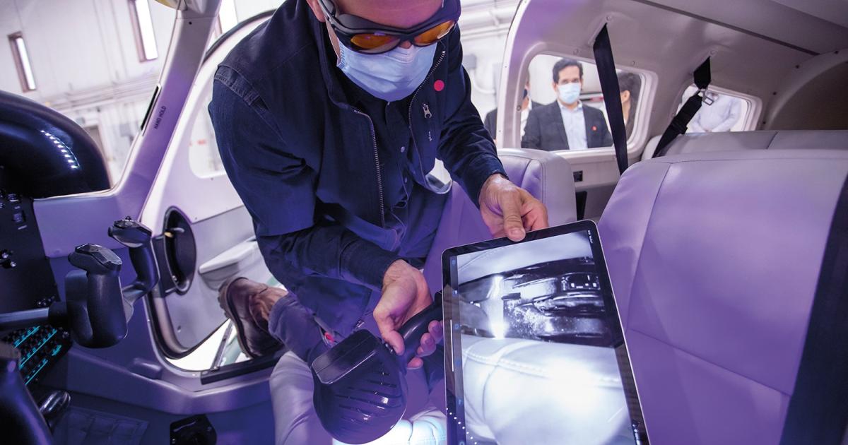 Kneeling in the cockpit of a UND aircraft, Joe Vacek, associate professor of aviation at UND, shines SafetySpect’s handheld contamination detection and disinfection light while checking the results on a tablet. Photos by Mike Hess/UND Today